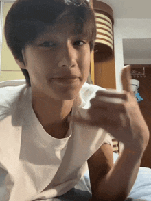 a young man laying on a bed giving a thumbs up sign