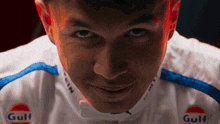 a close up of a person 's face with gulf logos on his shirt