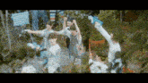 a group of young men are playing with water guns in a garden .