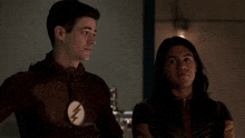 two men are standing next to each other and one of them has a flash logo on his chest