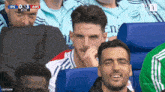 a man is sitting in the stands watching a soccer game .