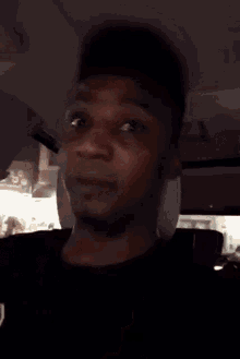 a man in a black shirt is making a funny face with his finger in his mouth