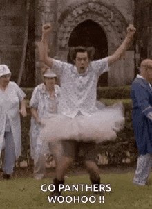 a man in a tutu is dancing in front of a group of people and shouting .