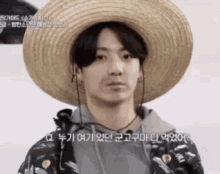 a man wearing a straw hat and headphones is looking at the camera .
