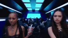 a group of women are sitting on a bus and one of them is holding a coke