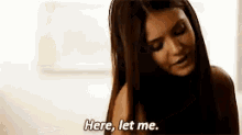 a woman with long hair is standing in front of a window and says `` here , let me . ''