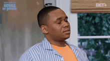 a man in a blue and white striped shirt is standing in front of a sign that says house of payne