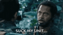 a man with a beard is talking to another man in the woods .