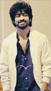 a man with a beard is wearing a white jacket and a black shirt