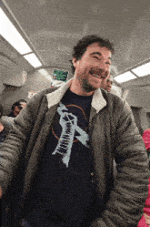 a man wearing a shirt that says ' x ' on it is smiling on a train