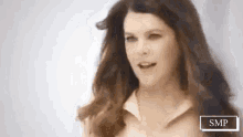 a woman with long brown hair is smiling and looking at the camera .