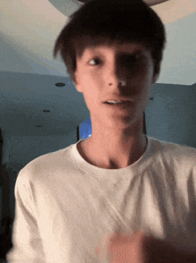 a young man wearing a white t-shirt is making a funny face