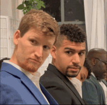 a man in a blue suit is standing next to another man