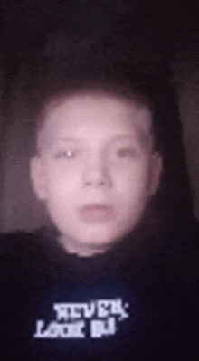 a young boy is taking a selfie with a black shirt on that says steve 's love dj .