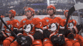 a group of hockey players wearing red jerseys with ducks on them are sitting in the stands