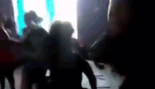 a group of people are dancing in a dark room .