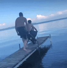 a man pushing another man in a wheelbarrow down a pier
