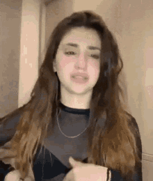 a woman with long brown hair is wearing a black shirt and a necklace .