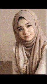 a woman wearing a hijab and a scarf is smiling