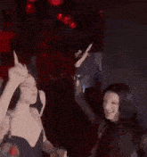 a couple of women are dancing in a club with their hands in the air .