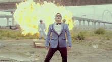 a man in a suit and bow tie is standing in front of a large fire