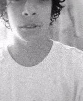a man with curly hair is wearing a white t-shirt