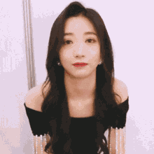 a woman in a black off the shoulder top with pearls on the sleeves
