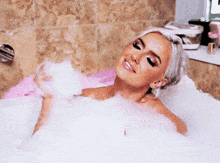 a woman is taking a bath in a tub filled with foam
