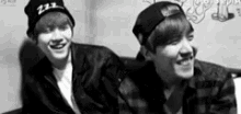 a black and white photo of two young men wearing beanies .