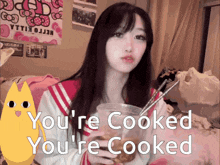 a girl is holding a cup of food with chopsticks and says you 're cooked