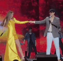a woman in a yellow dress is holding hands with a man in a gray suit