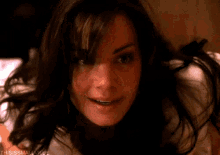 a close up of a woman 's face smiling while laying on a bed .