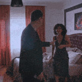 a woman in a green dress is standing next to a man in a suit in a bedroom