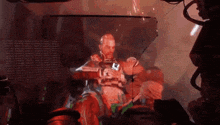 a man in a futuristic suit is sitting in a chair with a gun .