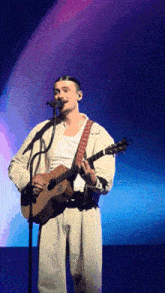 a man is playing a guitar and singing into a microphone