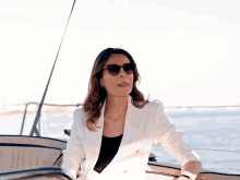 a woman wearing sunglasses is sitting on a boat in the water