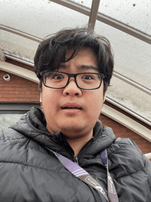 a man wearing glasses has a lanyard around his neck that says slacko