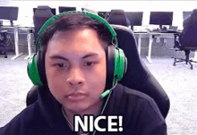 a man wearing green headphones and a microphone is sitting in a chair and says nice .