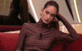 a woman sitting on a red couch with her hand on her head