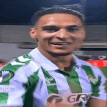 a soccer player wearing a green and white jersey with the letters gr on the front