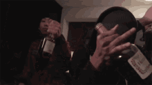 a person is holding a bottle of alcohol in their hand and giving the middle finger .