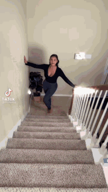 a woman is standing on the bottom of a set of stairs .