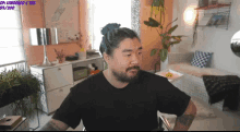 a man with blue hair and a beard is sitting in a living room with a purple sign that says lewgolo