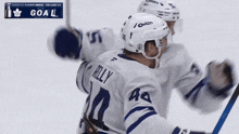two hockey players are celebrating a goal with a sign that says goal