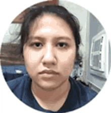 a close up of a woman 's face in a circle with a window air conditioner in the background .