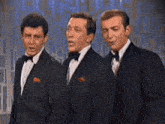 three men in tuxedos and bow ties are singing