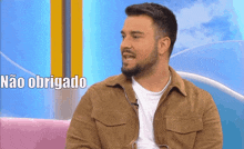 a man with a beard is sitting on a couch with the words não obrigado above him