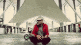 a man wearing a red adidas jacket squatting down