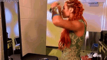 a woman with red hair is brushing her hair in front of a mirror in a room .