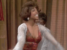 a woman in a red dress is dancing in front of a curtain with her arms outstretched .